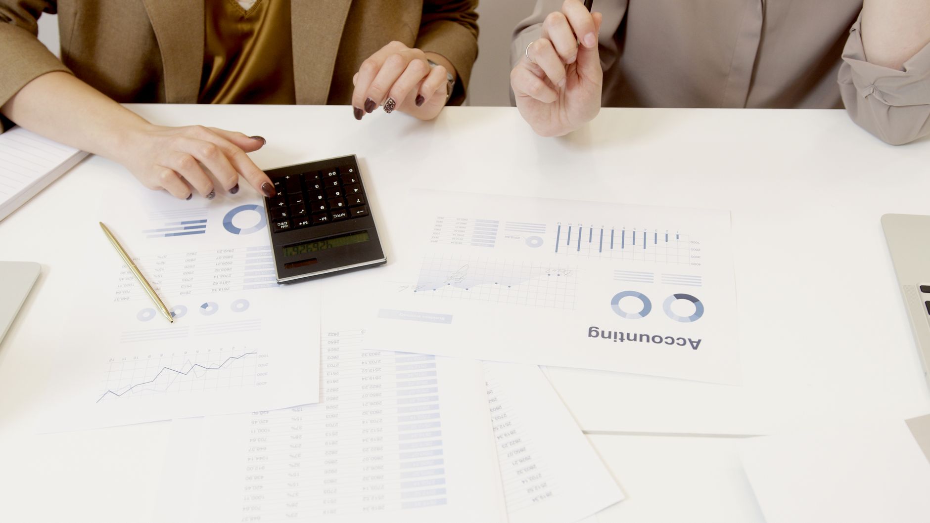Close-up of property deeds, keys and a calculator on a wooden table overlooking an Azores harbour