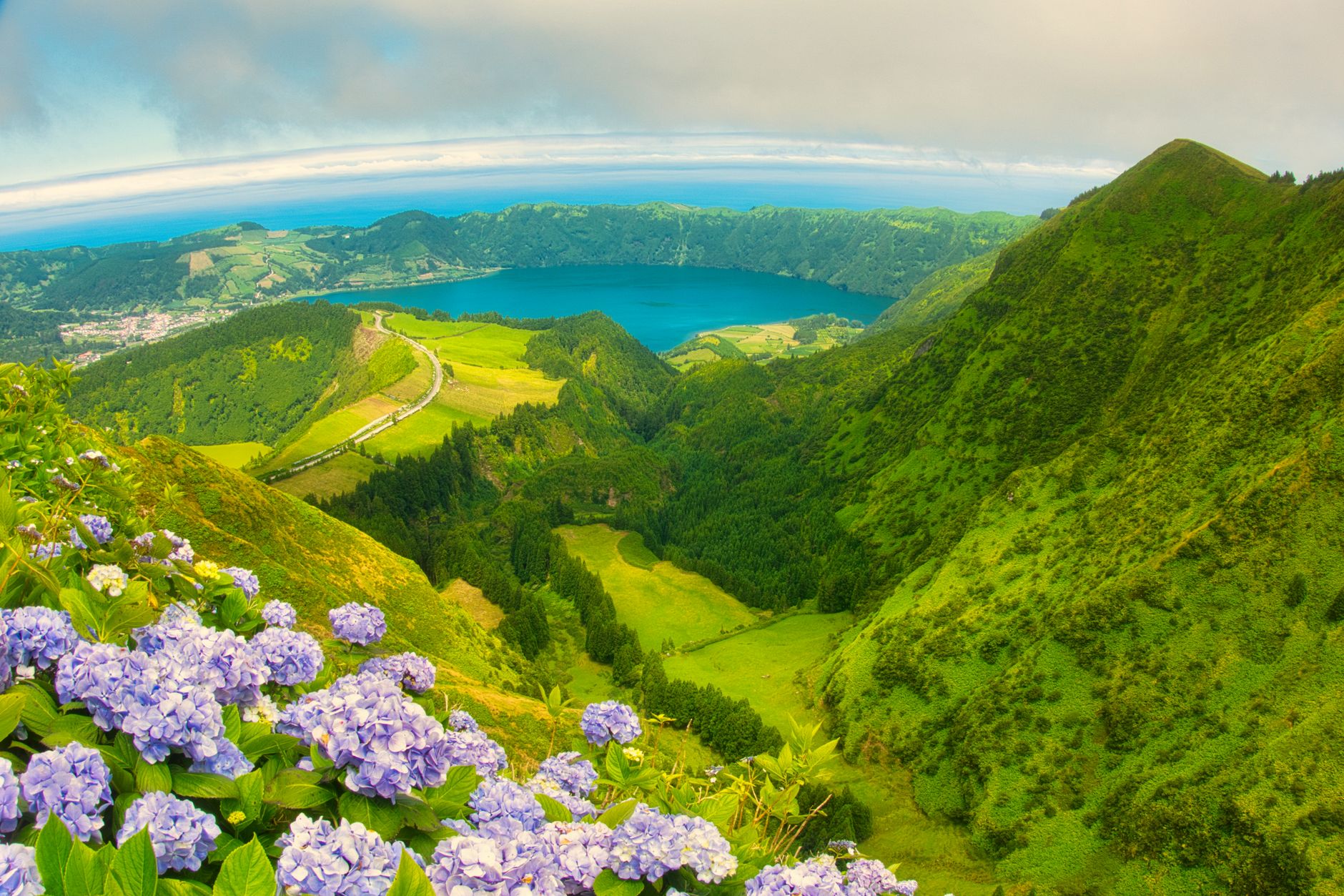 A wooden trail sign indicating a PR route in the Azores, with lush green vegetation