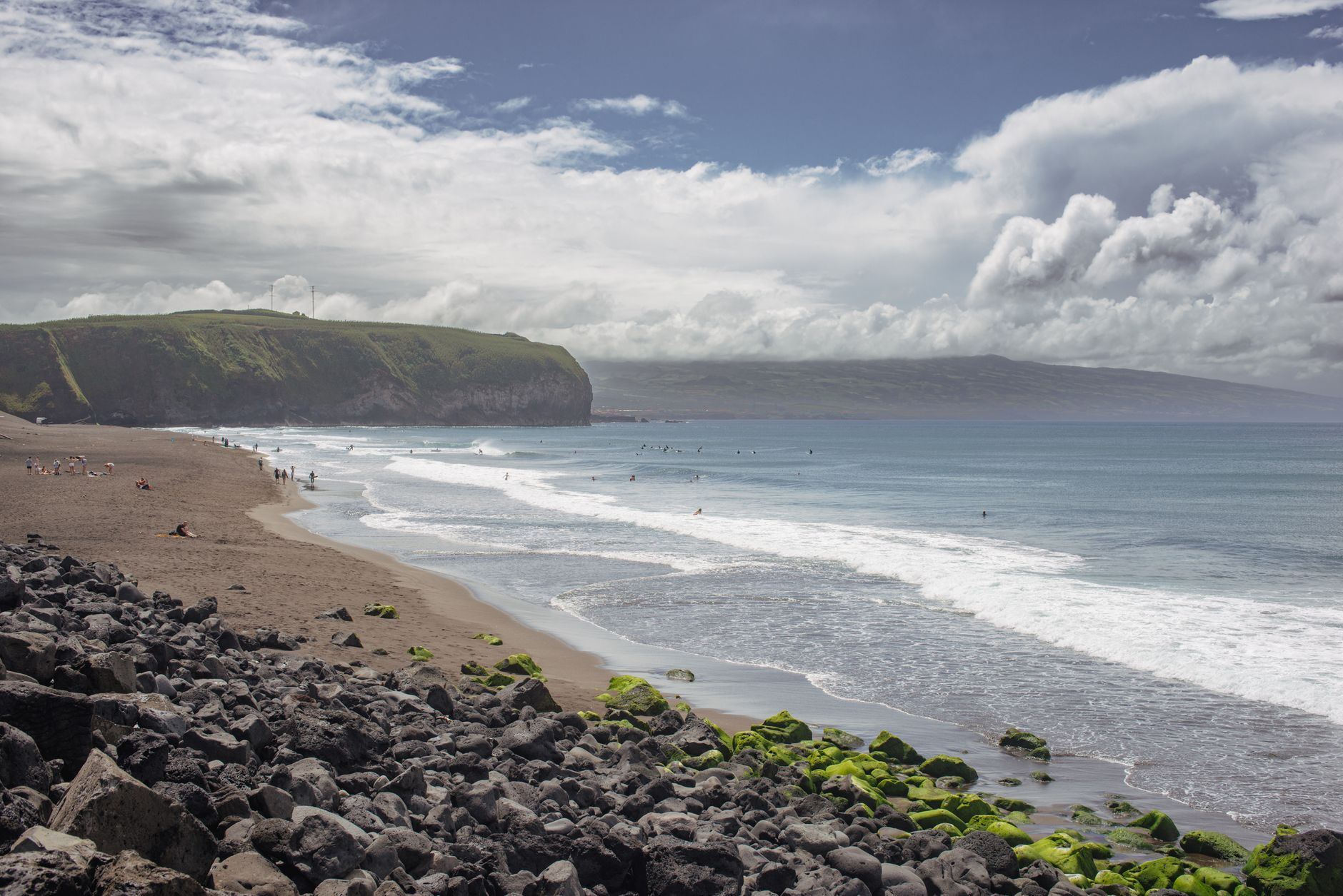 Dark-sand Praia do Monte Verde on the north coast of São Miguel with Atlantic waves and a promenade