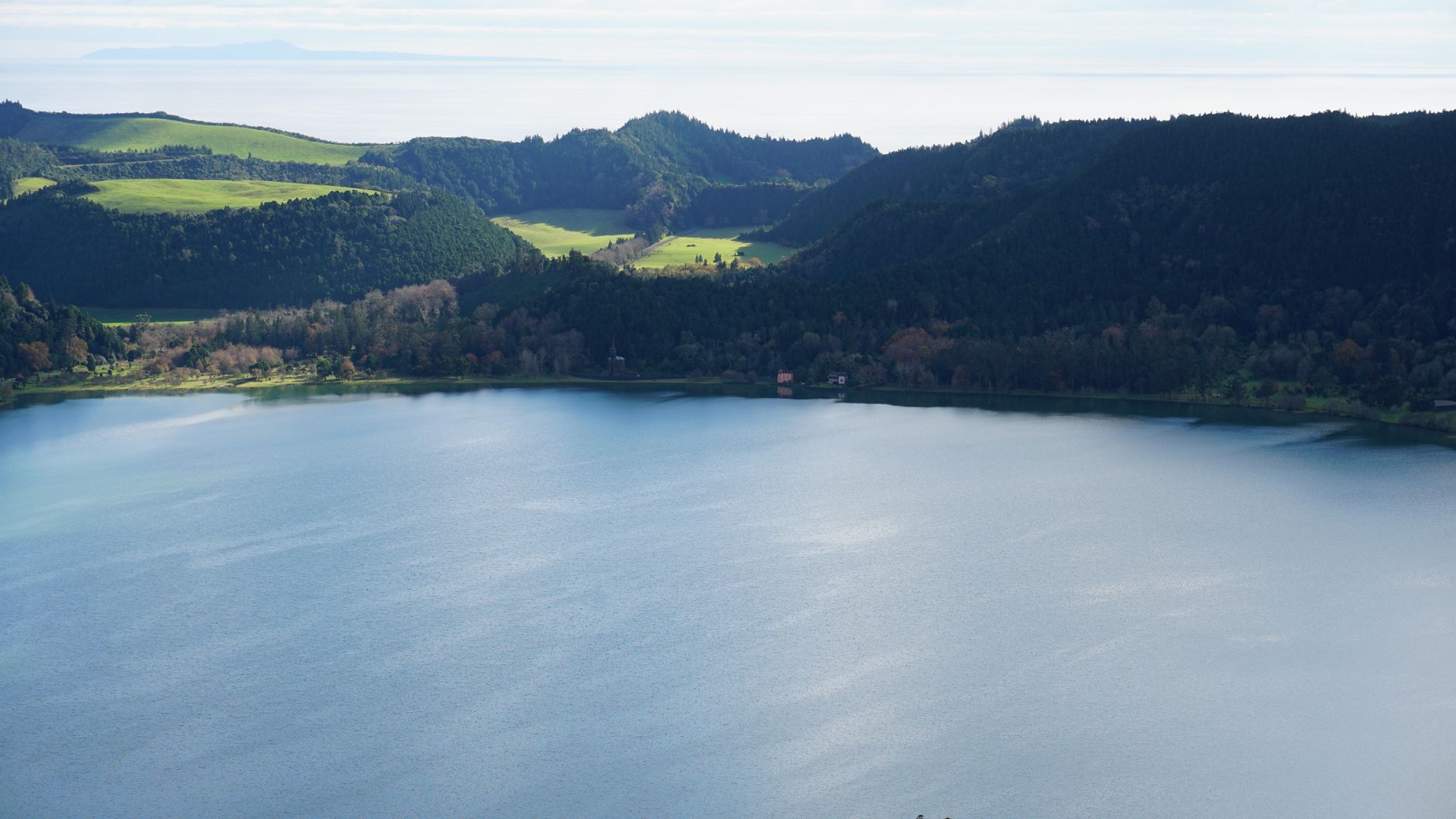 Steaming hot springs at Furnas with wooden walkways and visitors soaking in thermal pools.